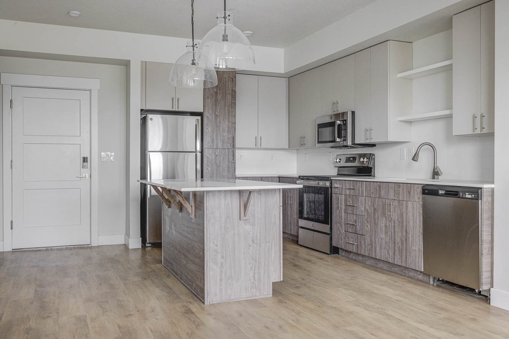 an empty kitchen with a large island and stainless steel appliances