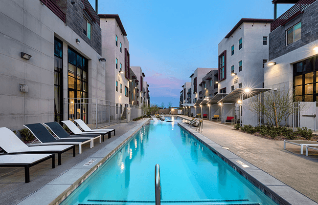 a swimming pool surrounded by apartment buildings at dusk