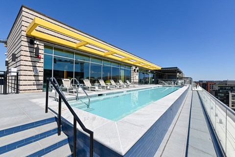 a pool on the rooftop of a building with a blue sky in the background