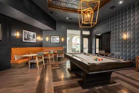 A pool table is in the middle of a room with a couch and chairs.