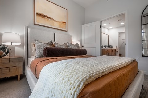 A bedroom with a large bed and a painting on the wall.