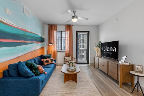 A living room with a blue sofa and a television displaying the word "Siena".