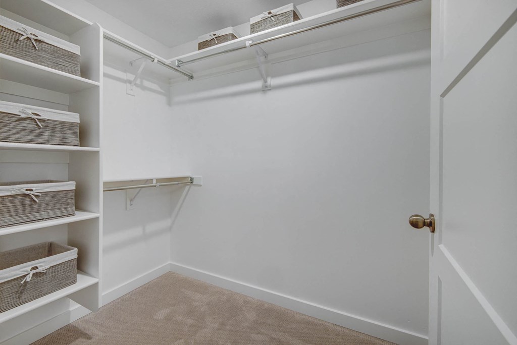 a walk in closet with white walls and shelves
