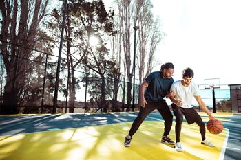 two men playing a game of basketball on a court