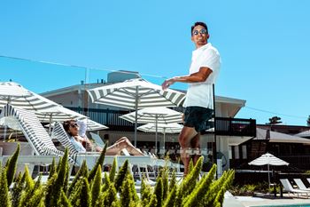 a man standing on the edge of a swimming pool in front of a hotel pool