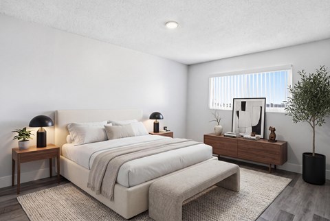 A well-lit bedroom with a large bed and a small tree.