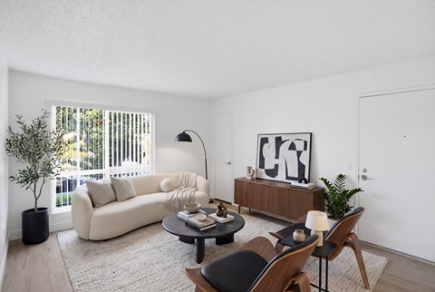 A living room with a white couch, a coffee table, and a painting on the wall.