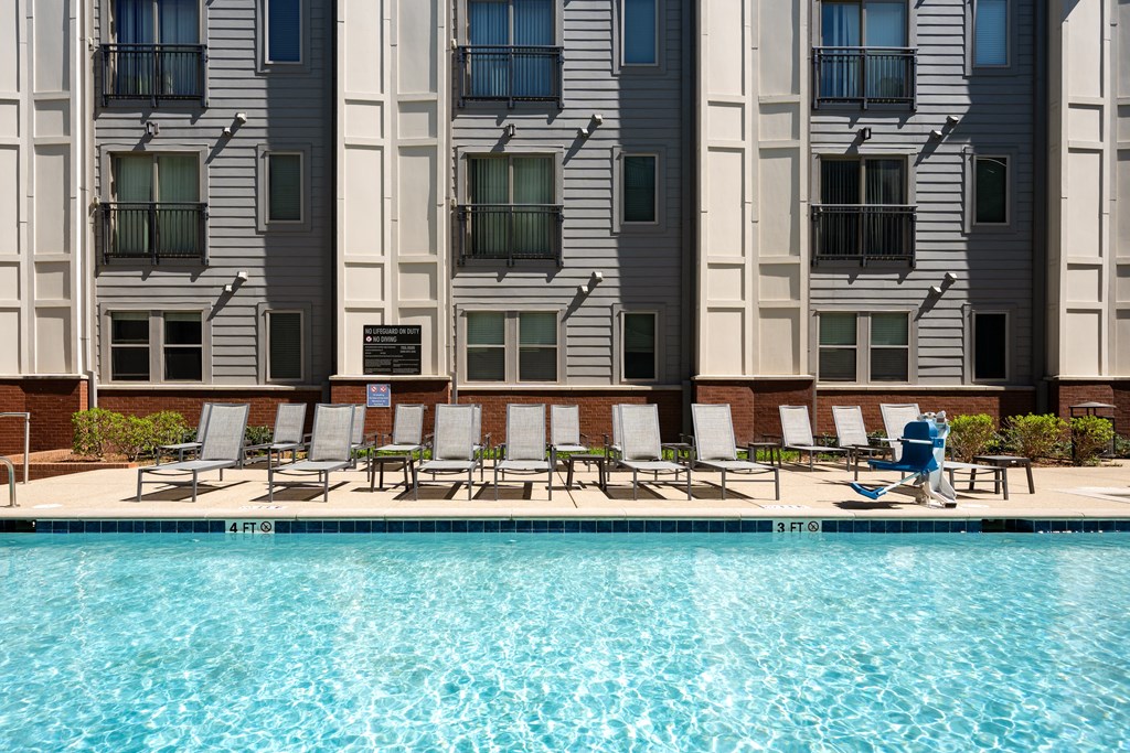 a person walking by a swimming pool in front of an apartment building