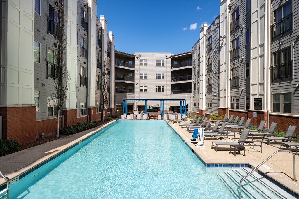 a swimming pool with lounge chairs in front of an apartment building