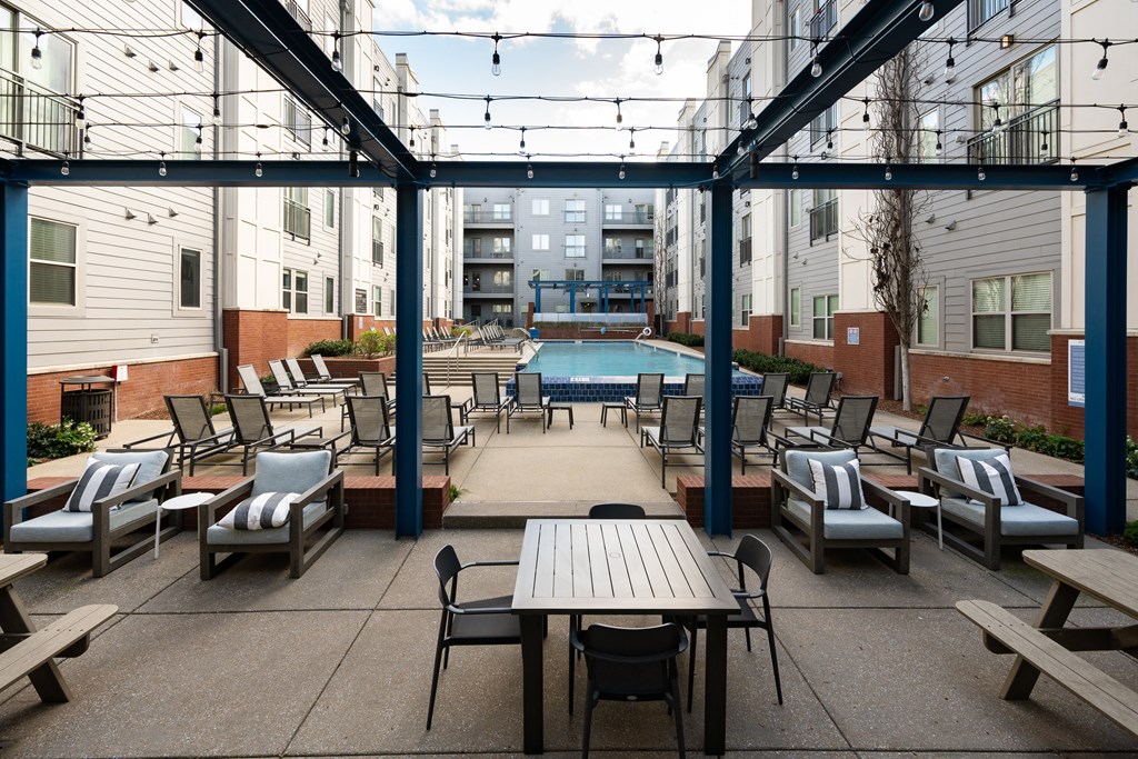 a patio with tables and chairs and a pool in the middle of an apartment building