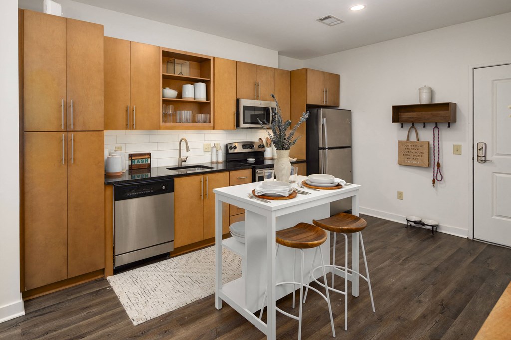 a kitchen with wooden cabinets and a white table with stools