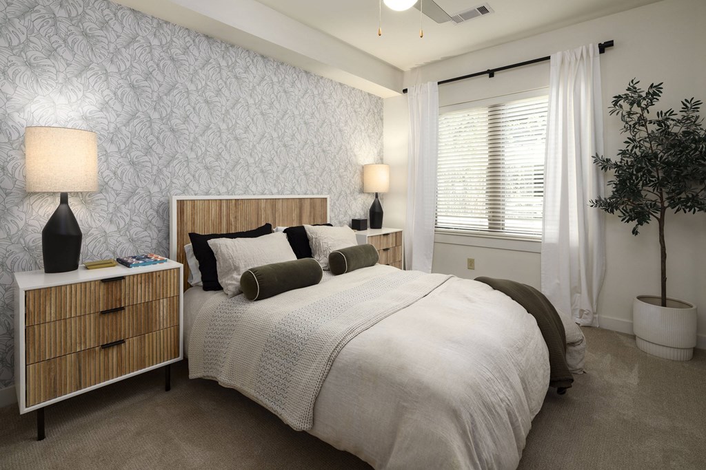 a bedroom with a bed and a window with white curtains