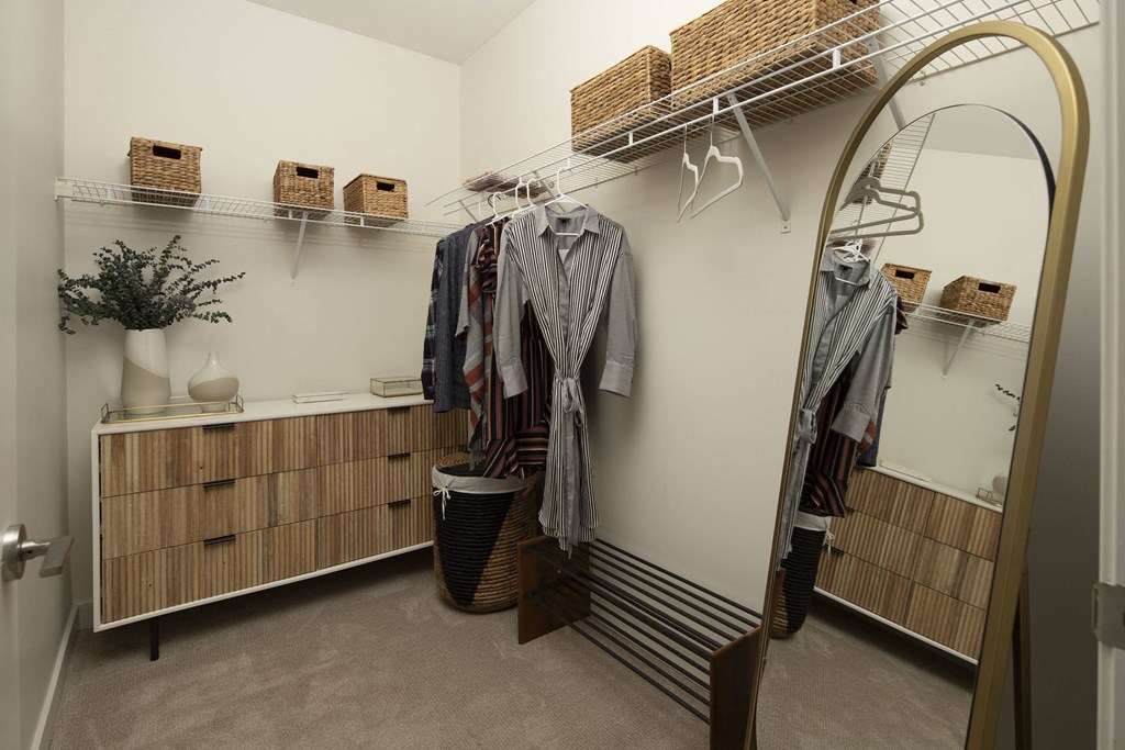a walk in closet with a mirror and clothes rack
