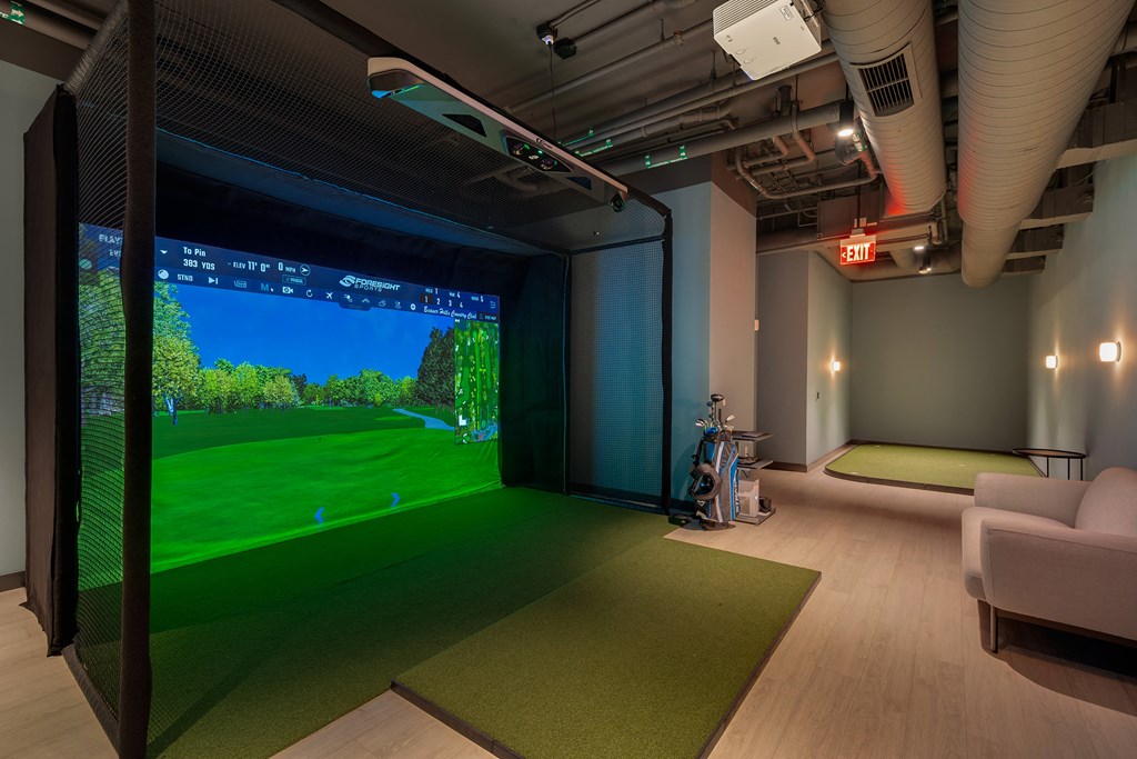 a room with a large screen tv and a golf simulator