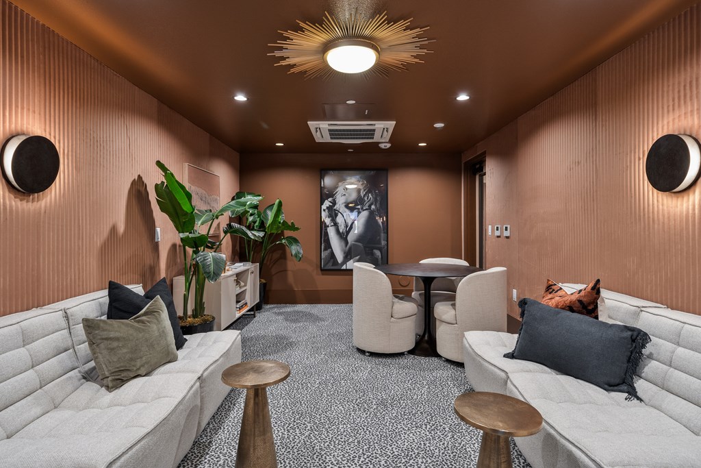 A modern living room with a grey carpet and a large painting on the wall.