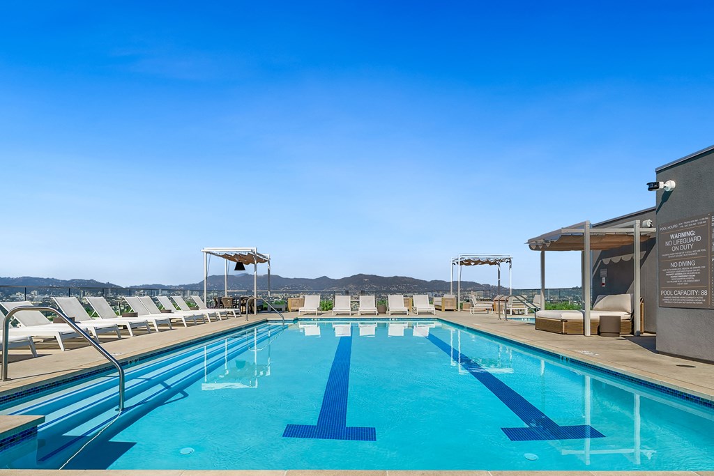 a swimming pool on the rooftop of a hotel with mountains in the background
