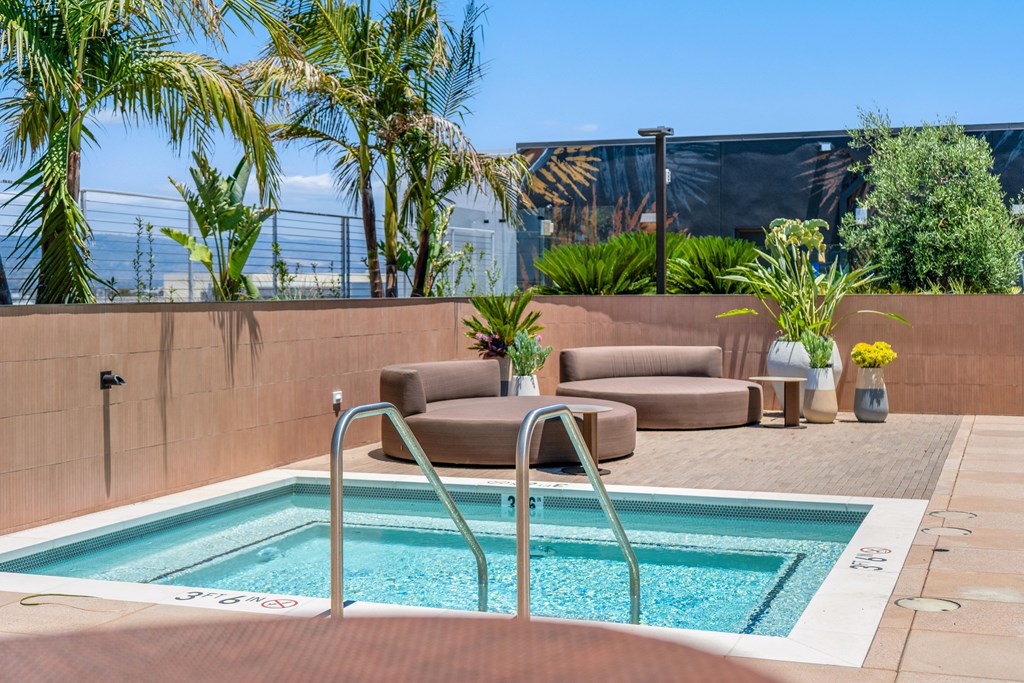A pool with a brown wall and a metal railing.
