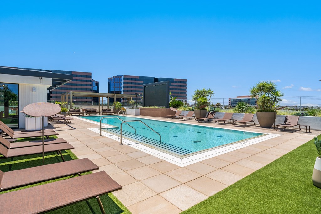 A large swimming pool surrounded by lounge chairs and umbrellas.