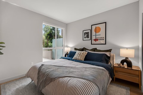 A bedroom with a large bed and a lamp on the side table.