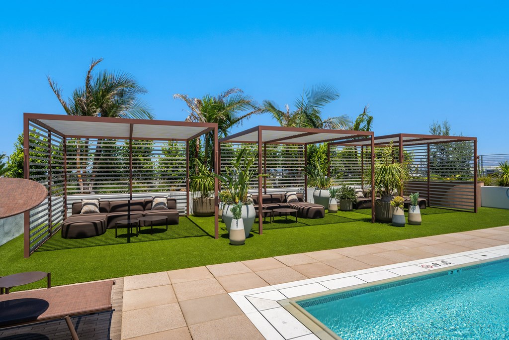 A poolside patio with a glass enclosure and lounge chairs.