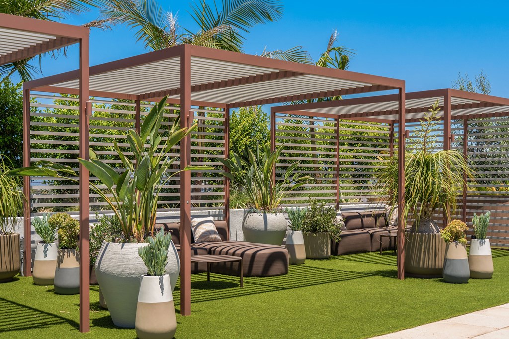 A patio with a pergola and potted plants.