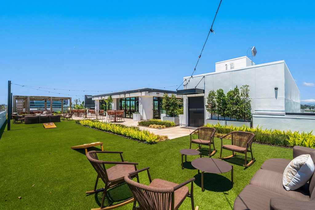 A patio with chairs and a table is set up on a lawn.