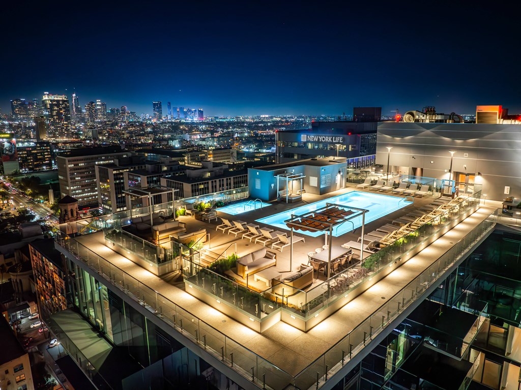 a rooftop terrace at night with a city in the background