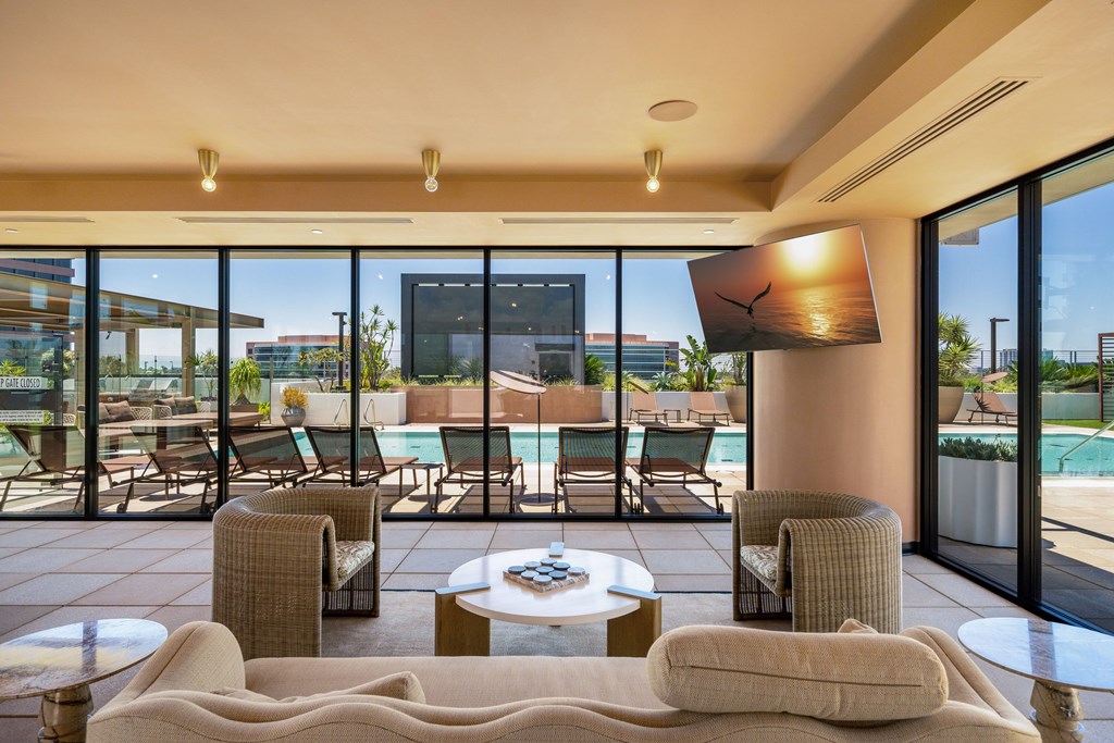A modern living room with a pool outside the window.