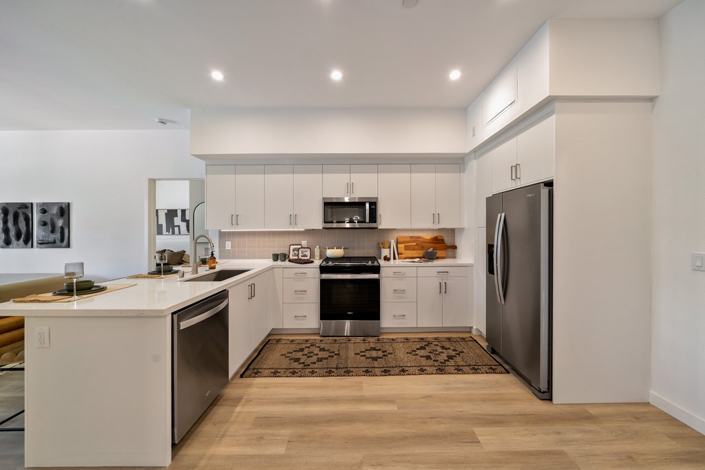 A modern kitchen with white cabinets and stainless steel appliances.