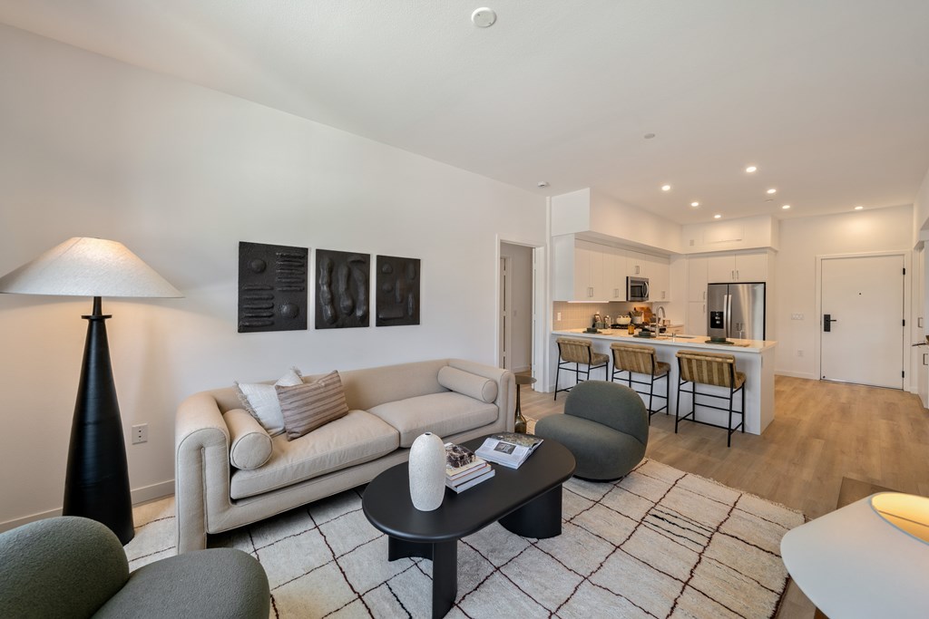 A living room with a white couch, a black table, and a lamp.