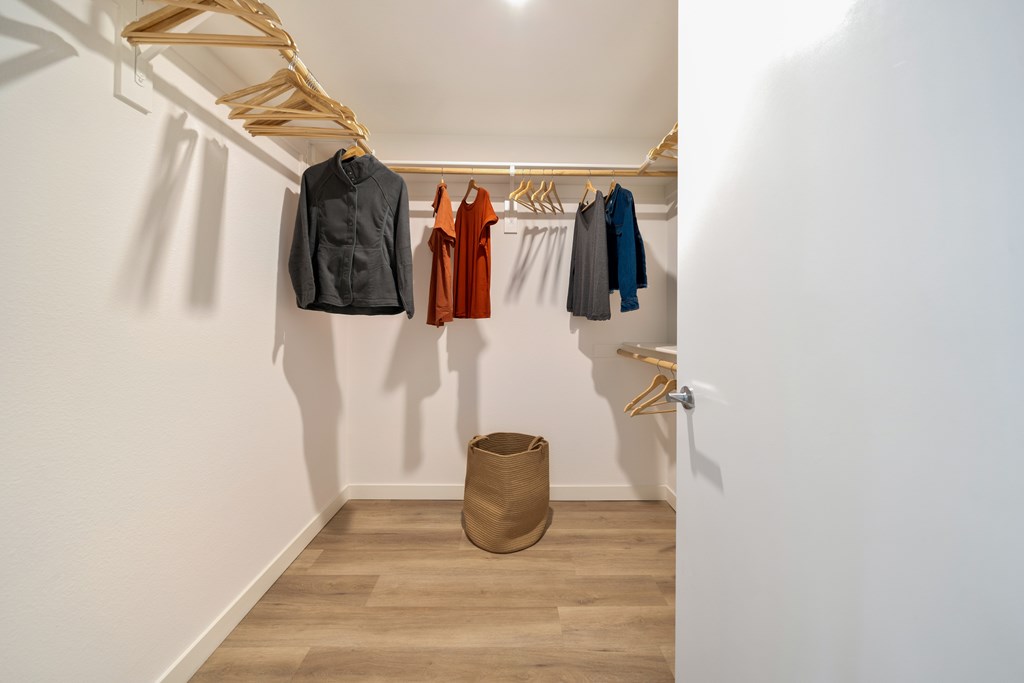 A room with clothes hanging on a rack and a basket on the floor.