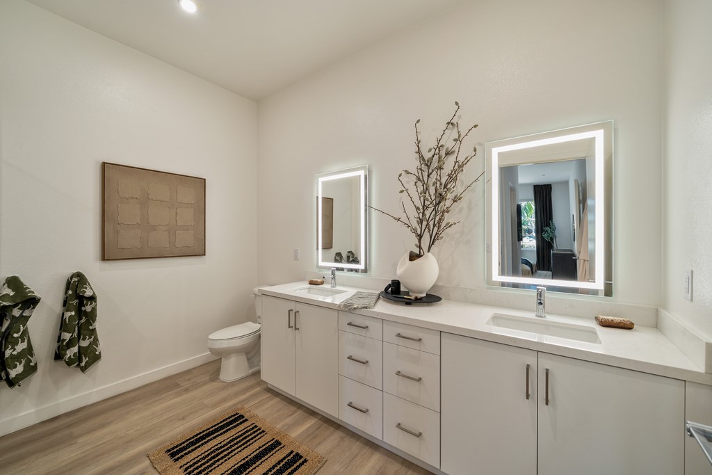 A bathroom with a toilet, sink, and mirror.