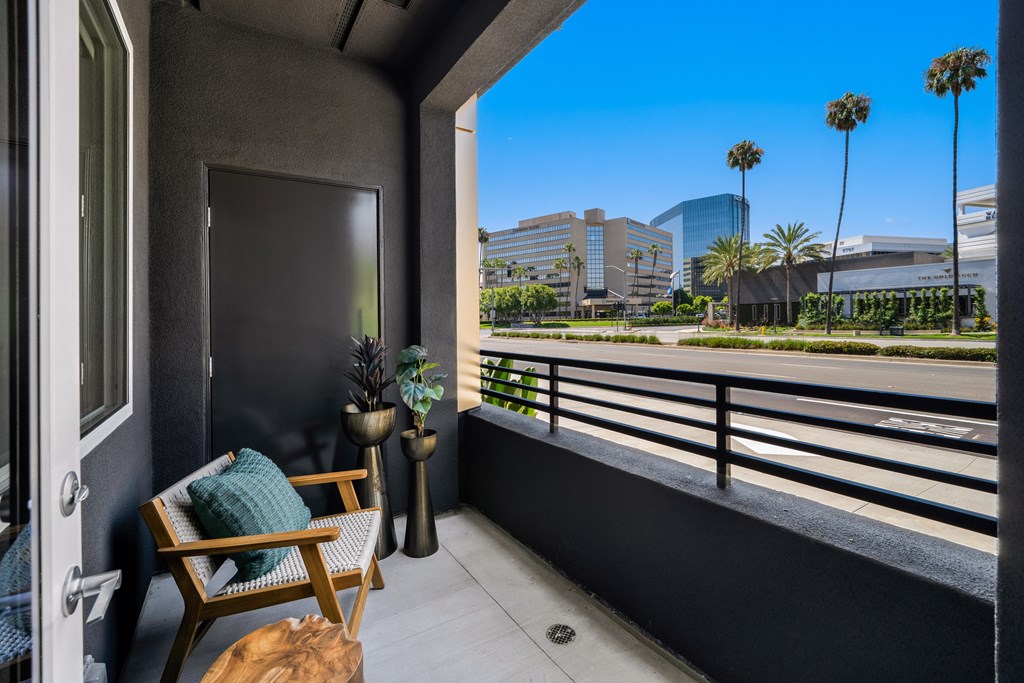 A balcony with a chair and a table with a plant on it.