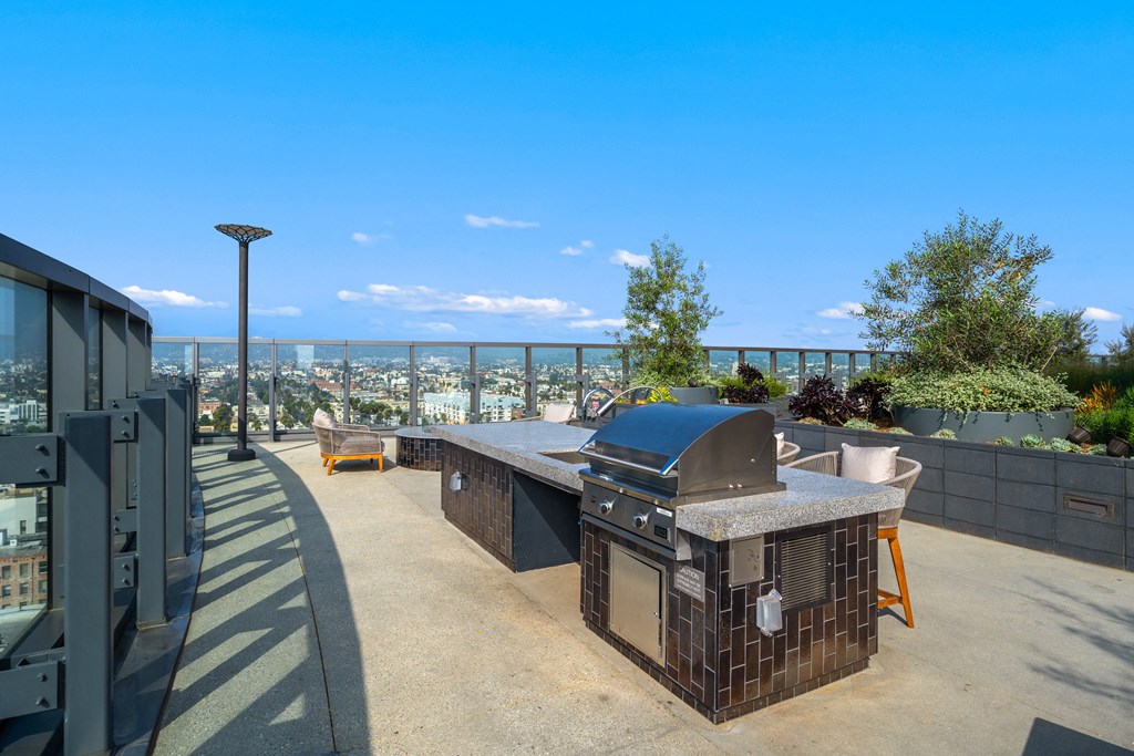 a rooftop patio with a barbecue grill and a view of the city