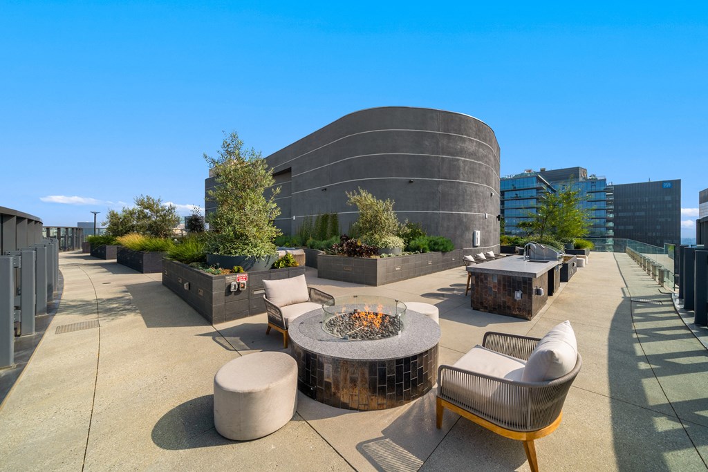 a rooftop patio with chairs and a fire pit