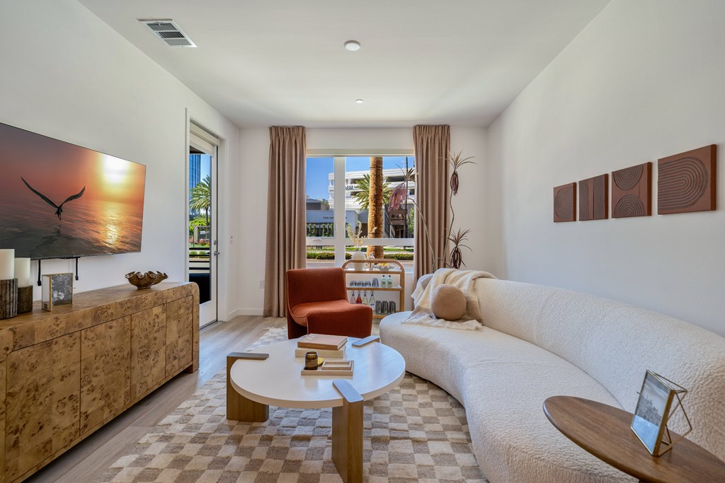 A living room with a white couch, a wooden coffee table, and a painting of a bird on the wall.