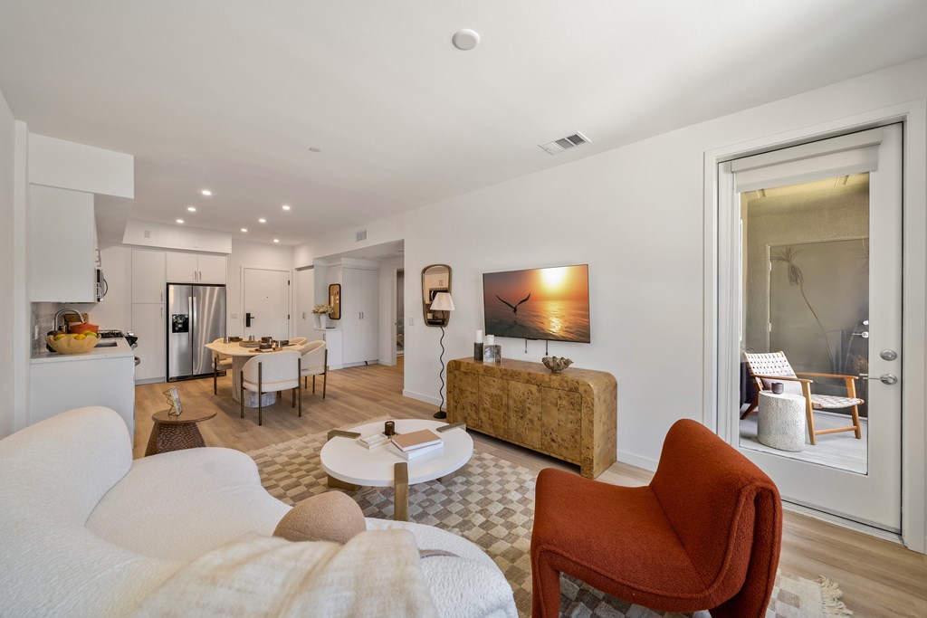 A living room with a white couch and a red chair.