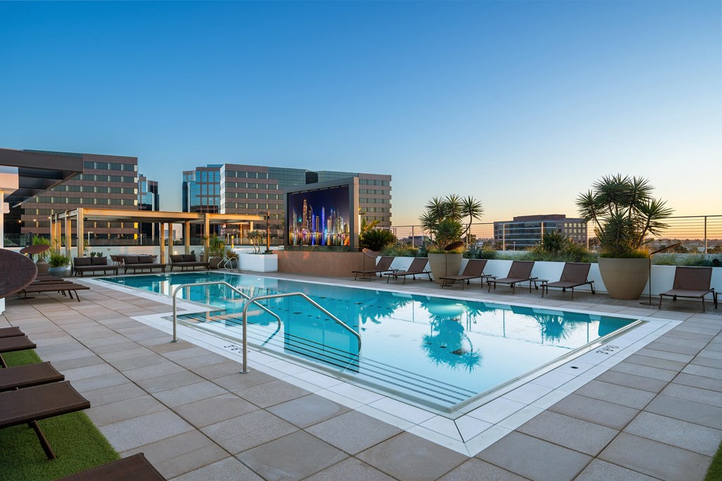 A large swimming pool with lounge chairs and a building in the background.