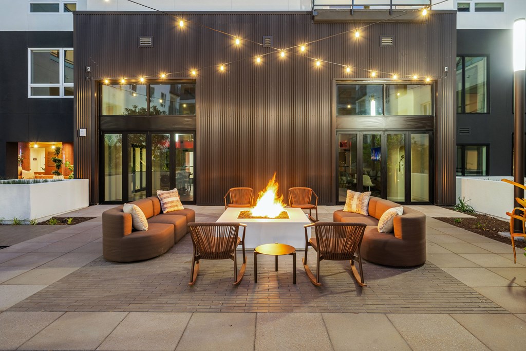 A patio with a fire pit and chairs.