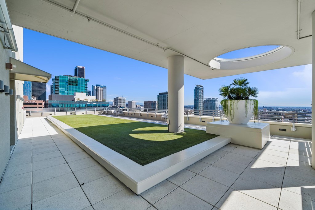 A rooftop patio with a white column and a green lawn.