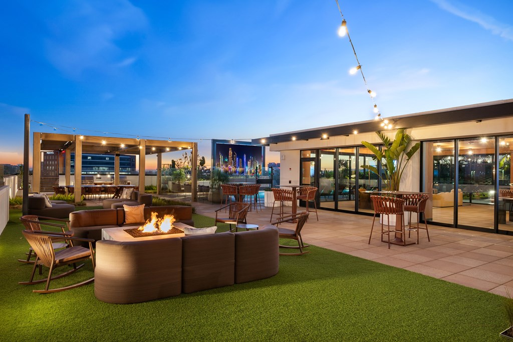 A modern outdoor seating area with a fire pit and string lights.