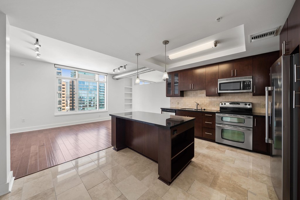A kitchen with a brown counter top and stainless steel appliances.