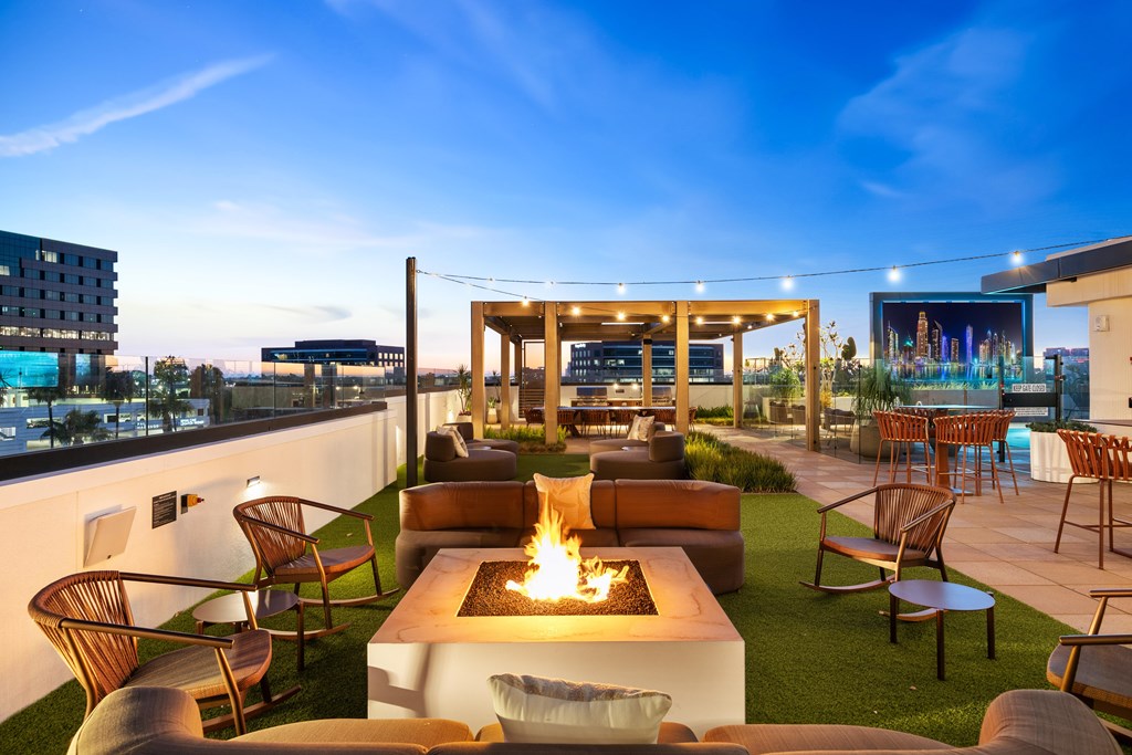 A rooftop patio with a fire pit and seating area.