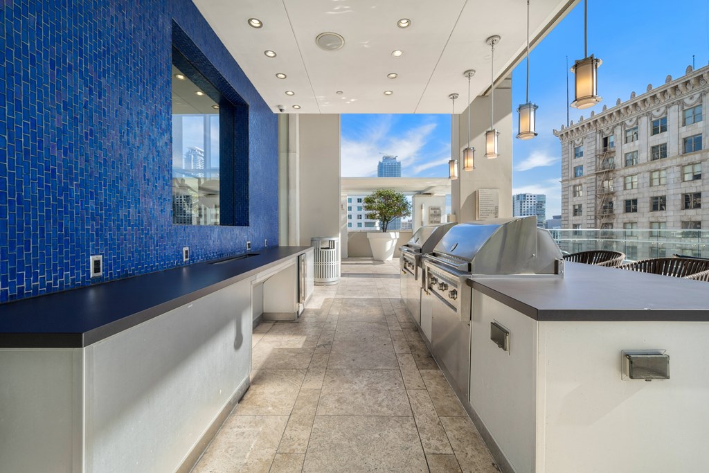 A modern kitchen with a blue tiled wall and a view of the city.
