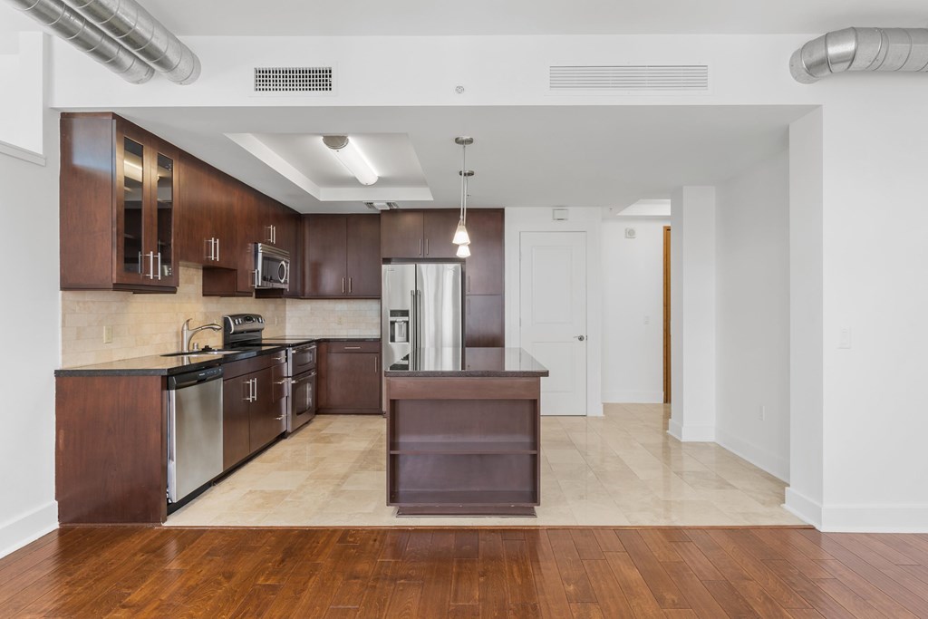 A kitchen with dark wood cabinets and a black counter top.