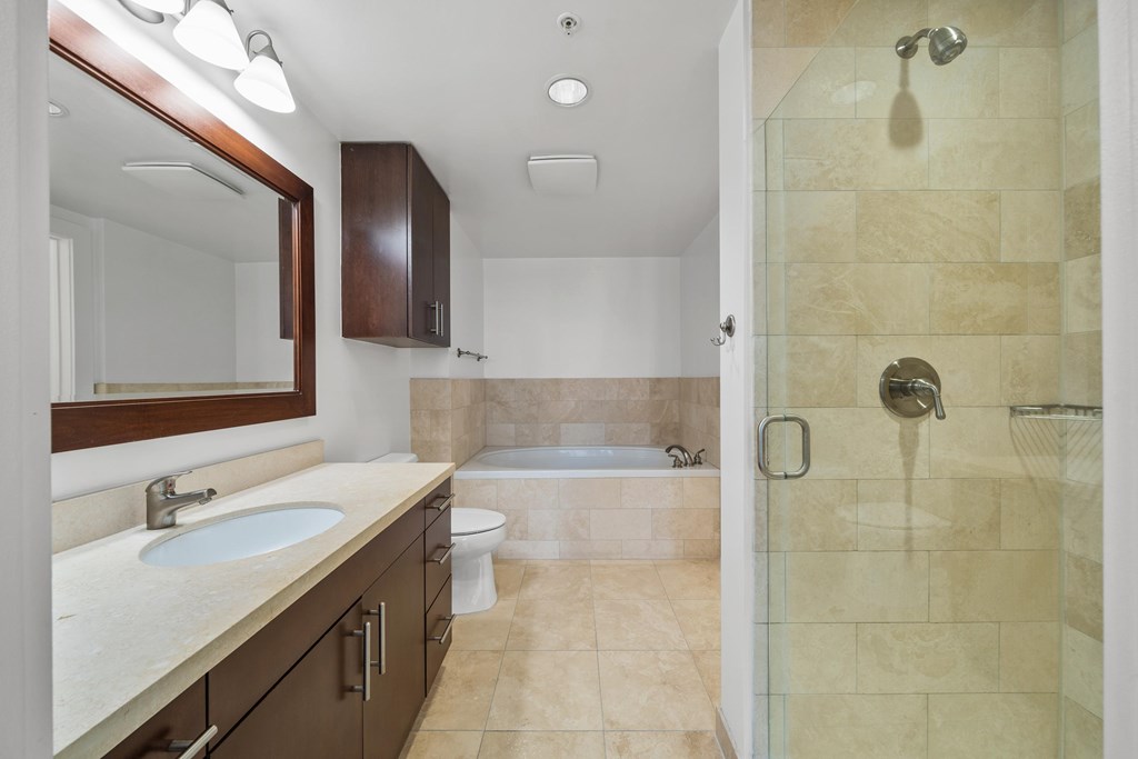 A bathroom with a sink, mirror, toilet, and shower.