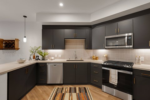 A modern kitchen with dark brown cabinets and stainless steel appliances.