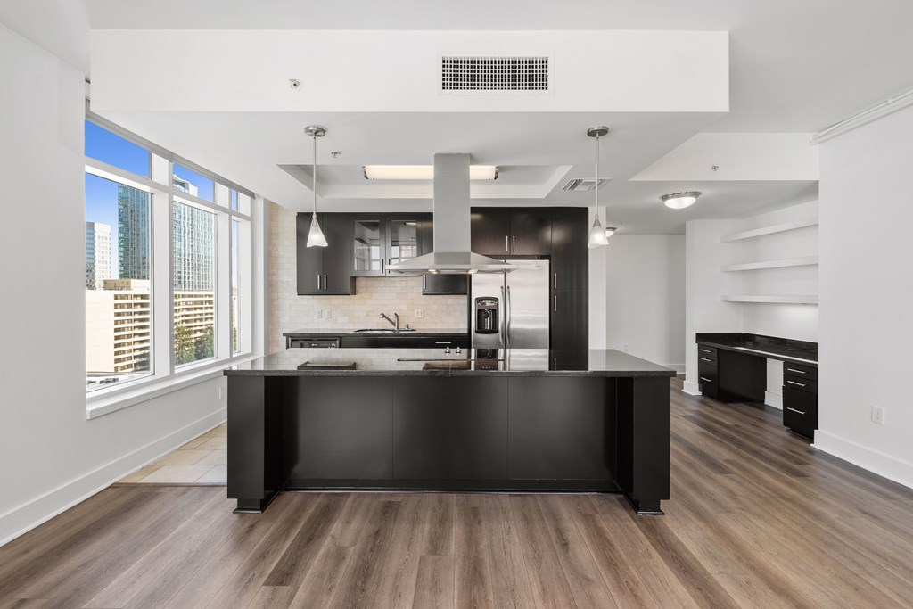 A modern kitchen with a black island and wooden floors.