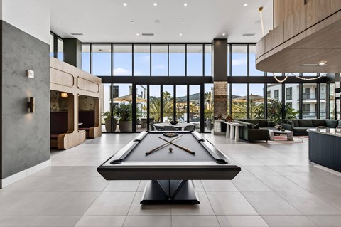 A pool table is in the middle of a room with a view of the mountains outside.