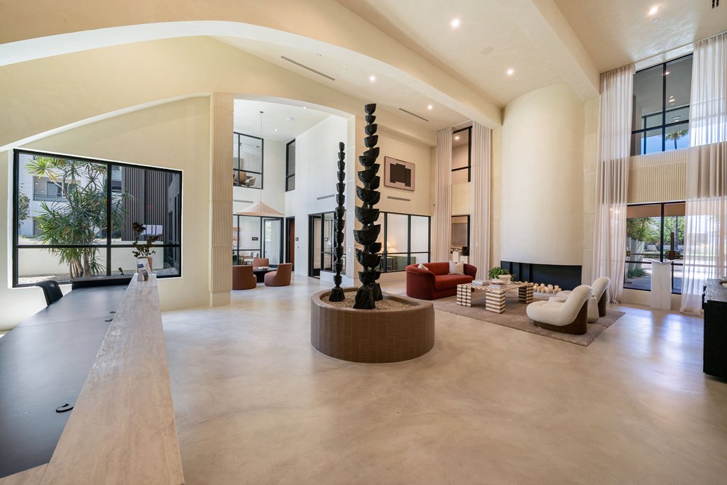 A modern living room with a long wooden bench and a tall black and white sculpture.